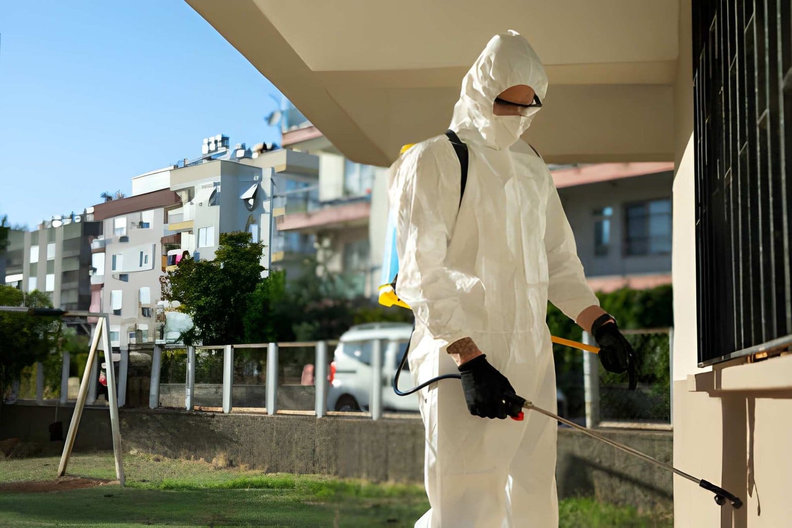 Pest control Vero Beach FL—technician in protective suit spraying exterior of residential building.