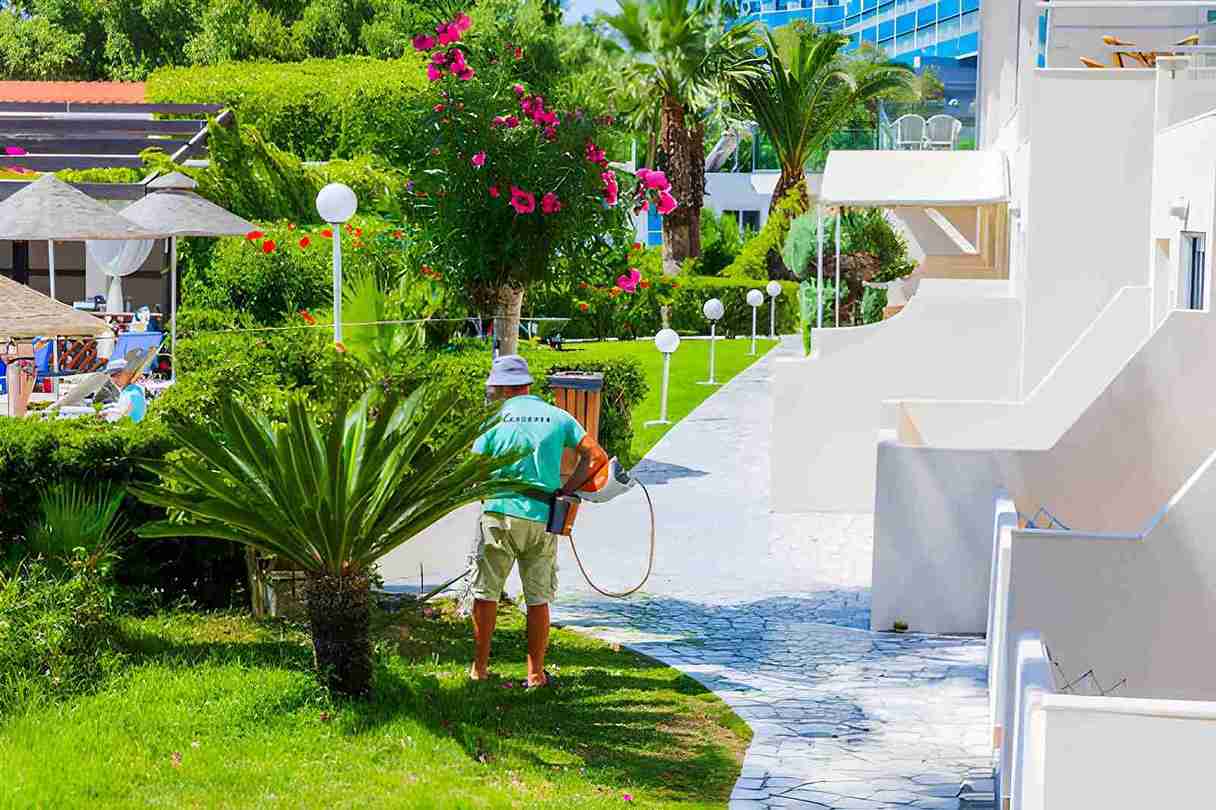 Coastal pest control of the Treasure Coast professional maintaining resort garden with leaf blower and tropical plants